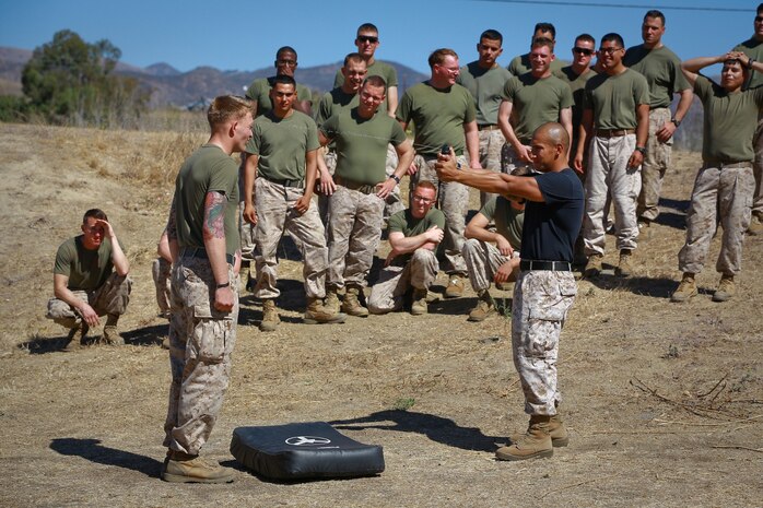 Staff Sgt. Hector Sanchez (right), nonlethal weapons instructor, 1st Law Enforcement Battalion, sprays a Marine serving with Delta Company, 1st Battalion, 1st Marine Regiment, in the face with pepper spay in front of a line of spectating Marines ready to endure a nonlethal weapons training course here, Oct. 1, 2013. Marines with Delta Company are preparing for a deployment to the Middle East where they’ll provide embassy security. Sanchez is a Chicago native.