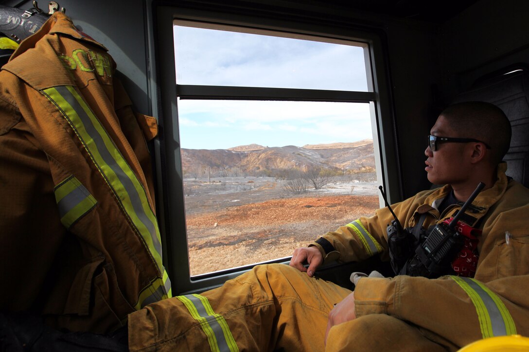 Jonathan Lim looks at the fire damage from inside his fire engine. Lim is a Firefighter paramedic with the Poway Fire Department.
