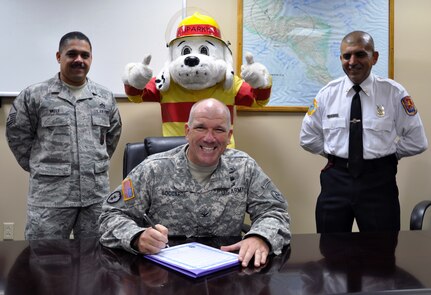 Col. Thomas Boccardi, Joint Task Force-Bravo commander, signs a proclamation declaring Fire Prevention Week at Joint Task Force-Bravo as U.S. Air Force Master Sgt. Juan Valle, Sparky the Fire Dog, and JTF-Bravo fire inspector Herberth Gaekel look on, Oct. 7, 2013. Fire Prevention Week was established to commemorate the Great Chicago Fire of 1871, and now serves as a way to keep the public informed about the importance of fire prevention. (U.S. Air Force photo by Capt. Zach Anderson)