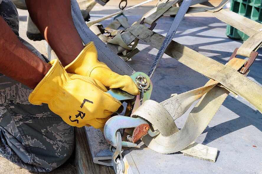 U.S. Air Force Tech. Sgt. Mark Natividad, 4th Operational Support Squadron aircrew flight equipment technician, tightens a cargo strap to a pallet at Seymour Johnson Air Force Base, N.C., Oct. 3, 2013. Airmen learned safety precautions and the basics of pallet building prior to participating in operational readiness exercise CORONET WARRIOR 13-04. (U.S. Air Force photo by Airman 1st Class John Nieves Camacho)