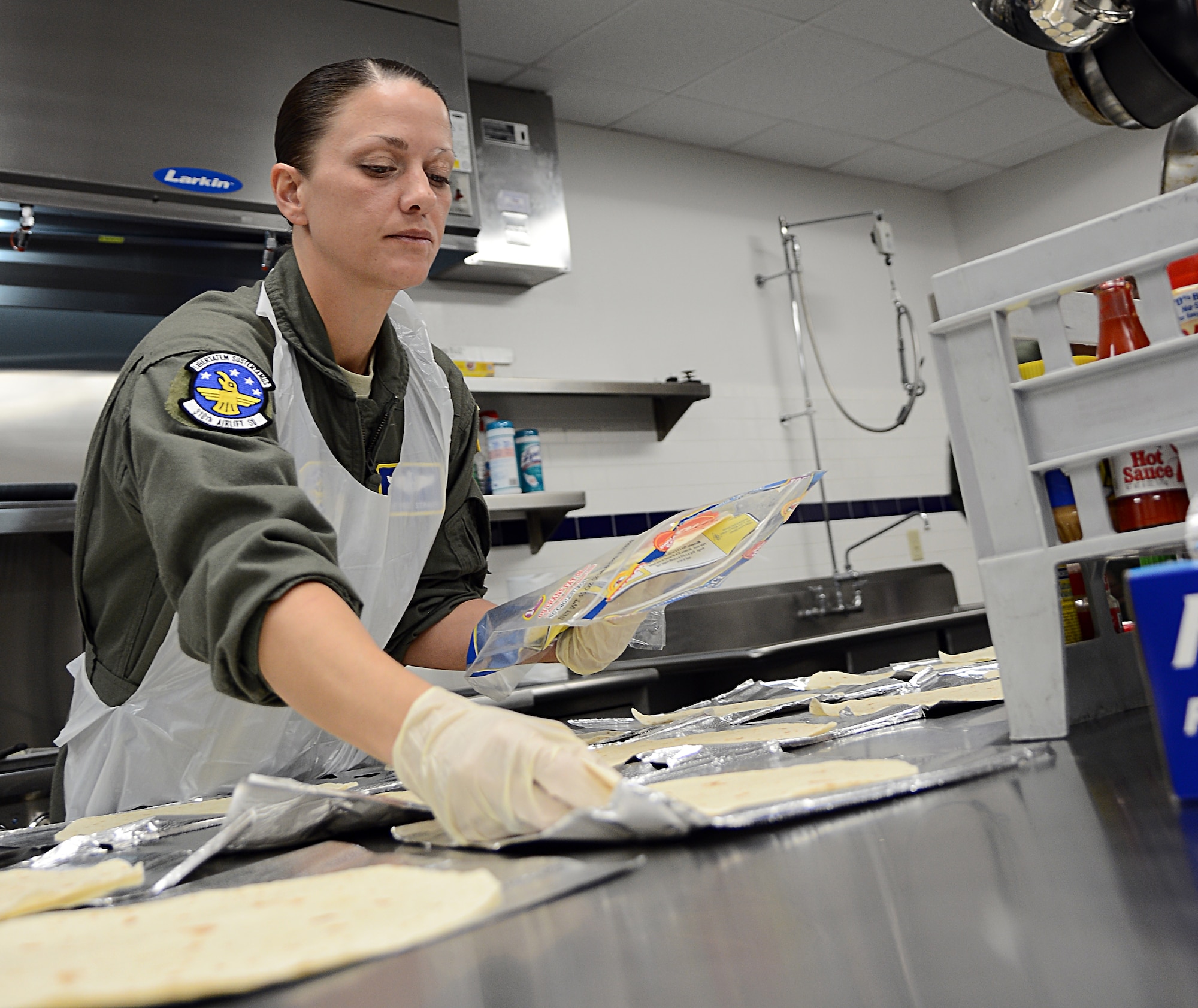 Tech. Sgt. Renee Strayer, 310th Airlift Squadron flight attendant, places tortillas on individual tin foil sheets at MacDill Air Force Base, Fla., Oct. 01, 2013. Strayer is currently training to become a certified flight attendant. (U.S. Air Force photo by Airman 1st Class Tori Schultz/Released)