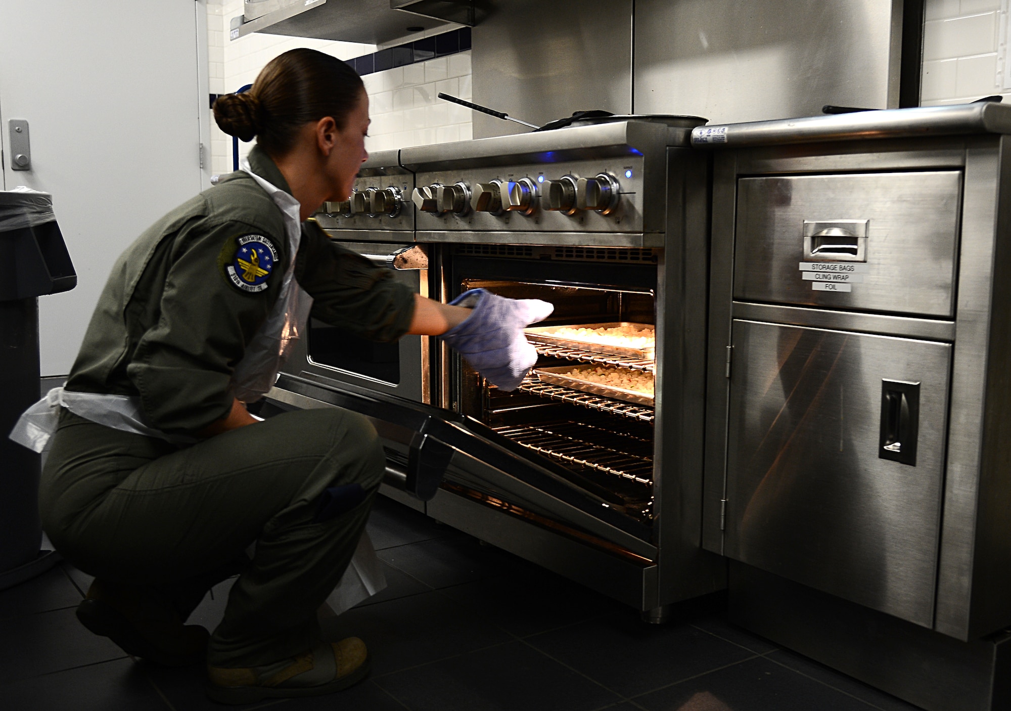 Tech. Sgt. Renee Strayer, 310th Airlift Squadron flight attendant, takes out diced potatoes from an oven at MacDill Air Force Base, Fla., Oct. 01, 2013. Strayer made breakfast burritos for 13 passengers for an early morning mission. (U.S. Air Force photo by Airman 1st Class Tori Schultz/Released)