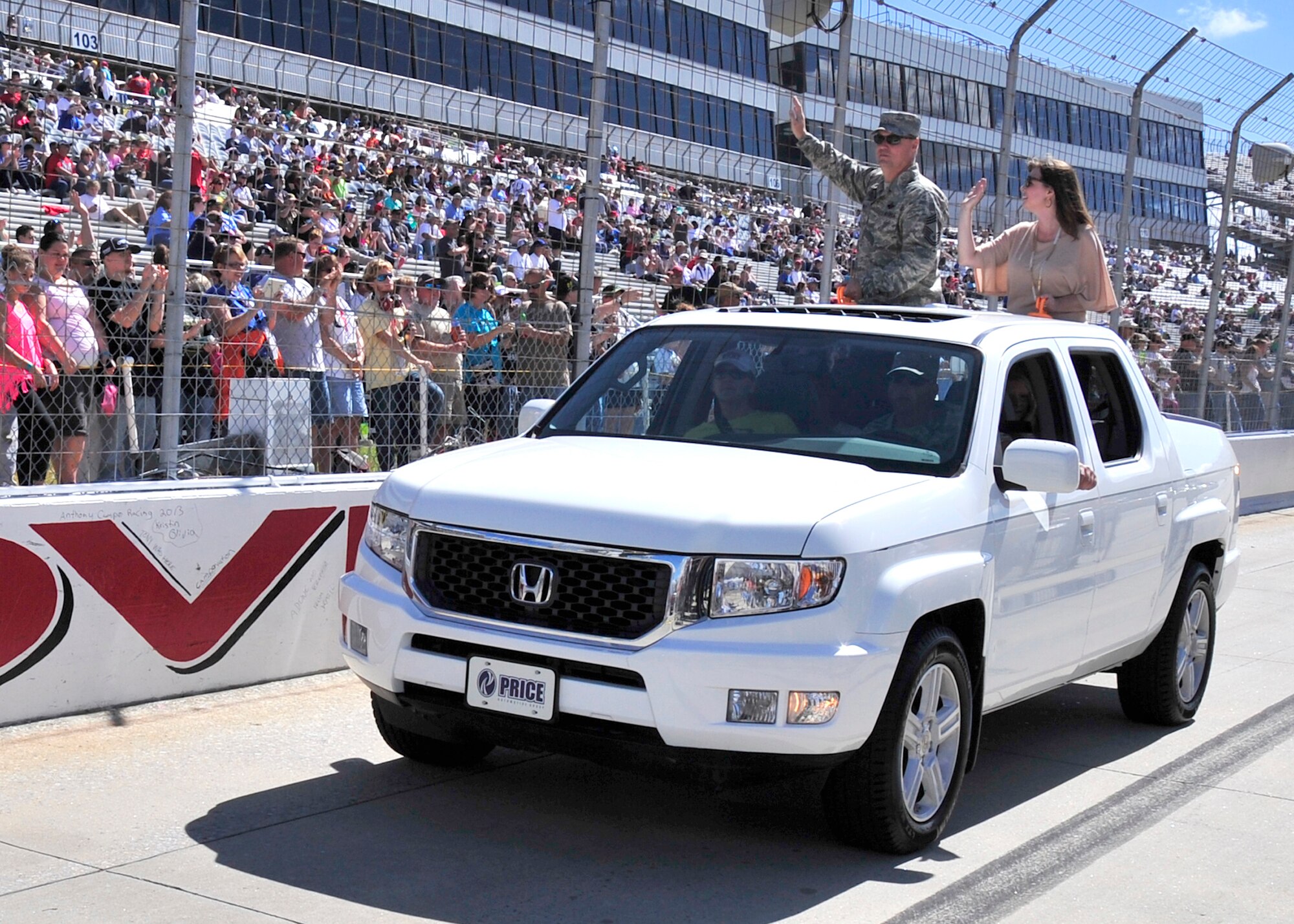 Chief Master Sgt. Stephen West, 512th Airlift Wing command chief representative, and his wife Nicole, wave to the crowd before the start of the AAA 400 Sept. 29, 2013, at Dover International Speedway in Dover, Del. West, an Air Force reservist, joined other Dover Air Force Base, Del., leadership for pre-race ceremonies, including a parade lap around the Monster Mile. (U.S. Air Force photo/Tech. Sgt. Chuck Walker)