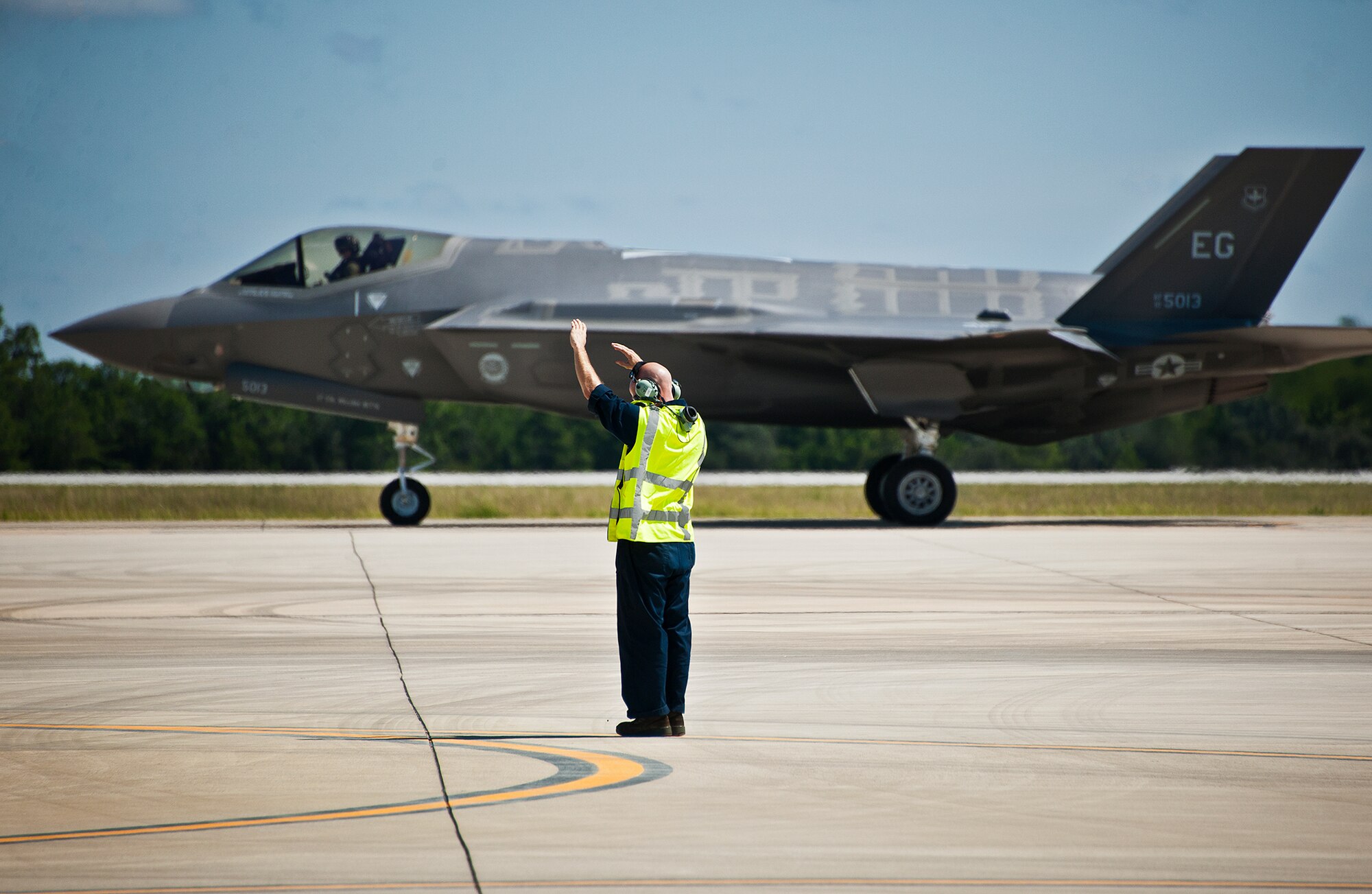 A 33rd Aircraft Maintenance Squadron maintainer prepares to marshal out his aircraft after a hot pit refueling session as an F-35A Lightning II rolls by.  Airmen, Marines and Sailors are refueling their F-35 variants for multiple sorties via 96th Test Wing fuel trucks while construction is completed on the 33rd’s hot pit area.  (U.S. Air Force photo/Samuel King Jr.)
