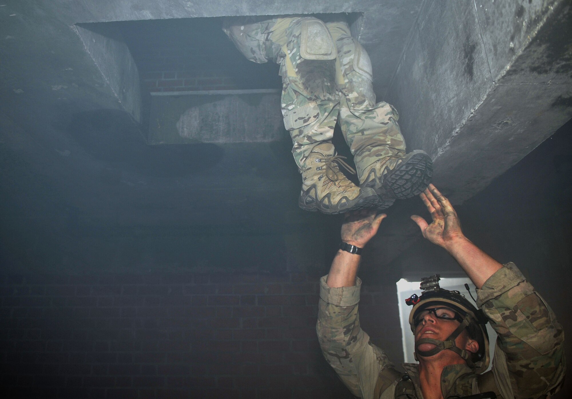 U.S. Air Force Senior Airman Jared Isenhart, 321st Special Tactics Squadron pararescuemen, helps Staff Sgt. Seth Lawrence up into the attic of a building Oct. 2, 2013, on RAF Mildenhall, England, during a confined-space extraction exercise. Airmen from the 321st STS routinely train on different scenarios in order to stay certified and prepared to execute any mission necessary. Pararescuemen are the most highly-trained and versatile Personnel Recovery specialists in the world, and will do whatever is required to deny the enemy a victory and bring our warriors home to fight another day. (U.S. Air Force photo by Airman 1st Class Kyla Gifford/Released) 