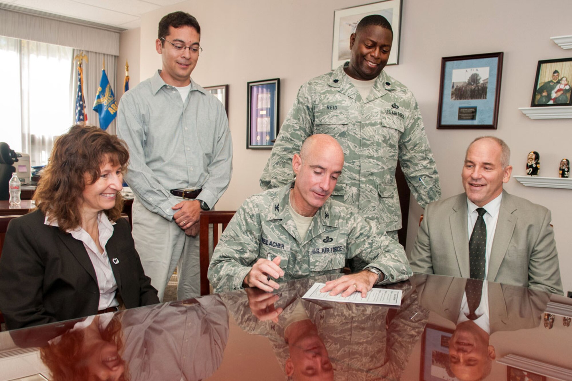 HANSCOM AIR FORCE BASE, Mass. -- Col. Lester A. Weilacher, 66th Air Base Group commander, recognizes October as Energy Action Month here by signing a proclamation in his office Nov. 8 as (left to right) Joan Croteau, David Wong, Lt. Col. Romero Reid and Thomas Schluckebier look on.  October is Energy Action Month and as part of a national campaign, led by the Department of Energy, Hanscom provides an opportunity to promote energy and water conservation awareness to the community. (U.S. Air Force photo by Rick Berry)