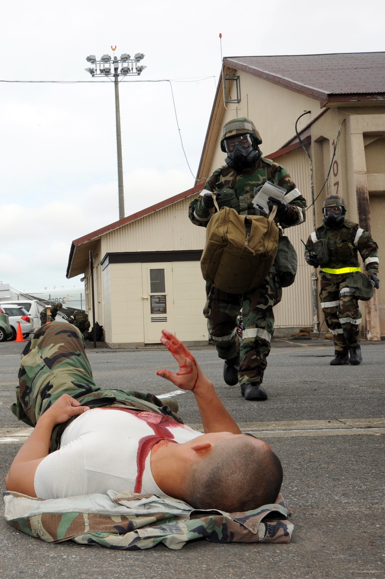 Capt. Juan Godinez, center, 35th Fighter Wing Post-Attack Reconnaissance team lead, and 2nd Lt. Jacqueline Mozingo, back, 35th Contracting Squadron, approach Staff Sgt. Earvin Bundang, 35th Medical Operations Squadron, to apply Self-Aid Buddy Care at Misawa Air Base, Japan, Oct. 7, 2013. Bundang served as a role player simulating injuries after a simulated attack during a week-long Operational Readiness Exercise. (U.S. Air Force photo by Senior Airman Derek VanHorn)