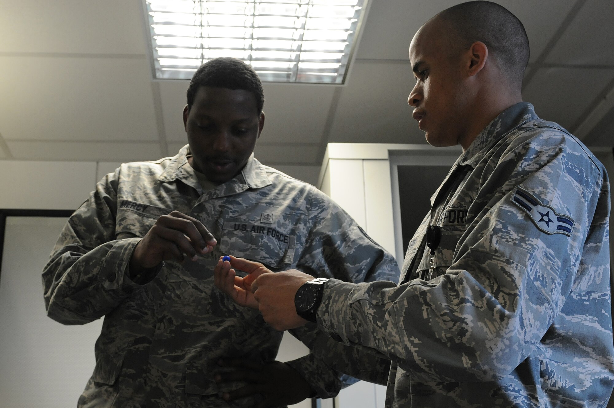 Airman 1st Class Allen Cherry, 86th Medical Group public health technician, explains to Staff Sgt. Alton Mercy, 86th Medical Group public health technician, how to insert hearing protection into someone’s ears to in order to prevent hearing loss, Oct. 1, 2013, Ramstein Air Base, Germany. The occupational health office offers hearing tests for military members who work in industrial hazard environments to ensure their hearing is at the right level to accomplish the mission. (U.S. Air Force photo/Airman 1st Class Holly Mansfield)