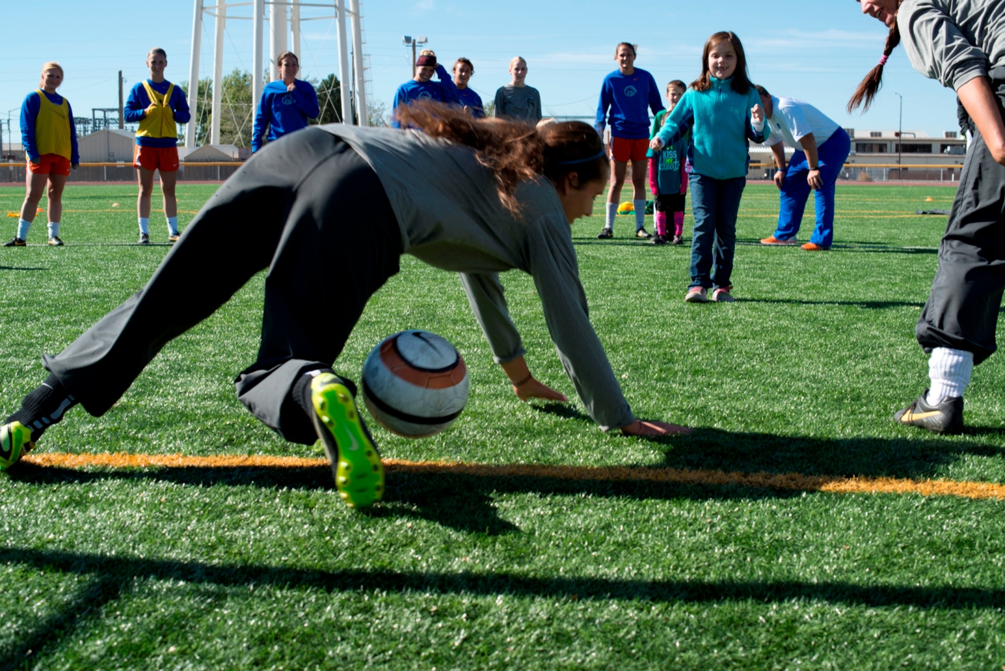 Eight-year-old Natalie Carlsness, daughter of Tech. Sgt. Tim Carlsness, 366th Operations Support Squadron, takes a shot at goal as not one, but two goal keepers, who both put in a pint-size effort to stop the riveting shot -- even diving at the passing ball -- at Mountain Home Air Force Base, Idaho, Oct. 5, 2013. The keepers were two of fourteen Boise State University ladies soccer players who visited base as part of their Military Appreciation Day. (U.S. Air Force photo by Master Sgt. Kevin Wallace/RELEASED)
