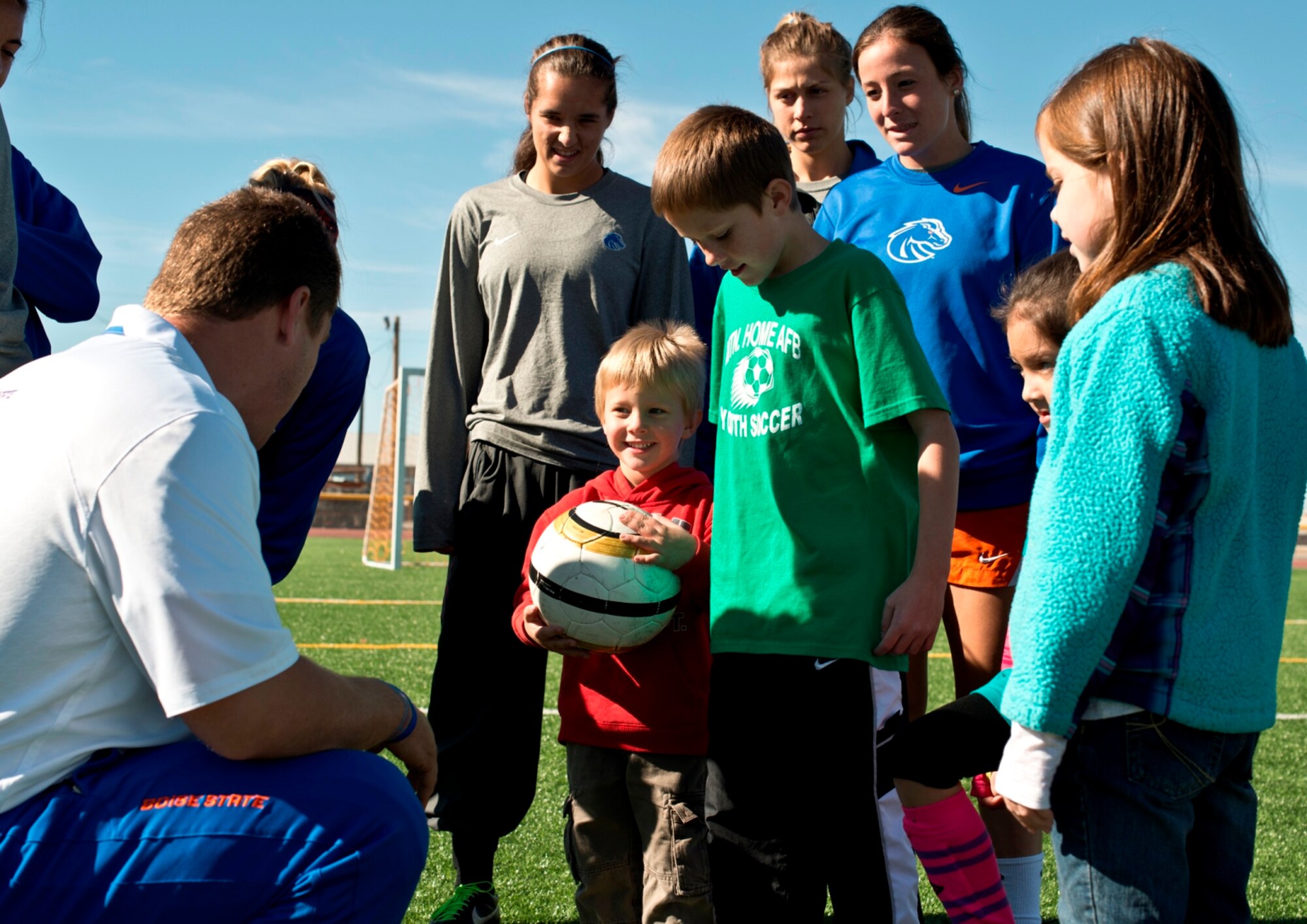 Ed Moore, Boise State University ladies soccer team assistant coach, shows base children how to pass with the inside of their cleats during a soccer clinic for military families at Mountain Home Air Force Base, Idaho, Oct. 5, 2013. The Broncos visited base as part of their Military Appreciation Day. (U.S. Air Force photo by Master Sgt. Kevin Wallace/RELEASED)