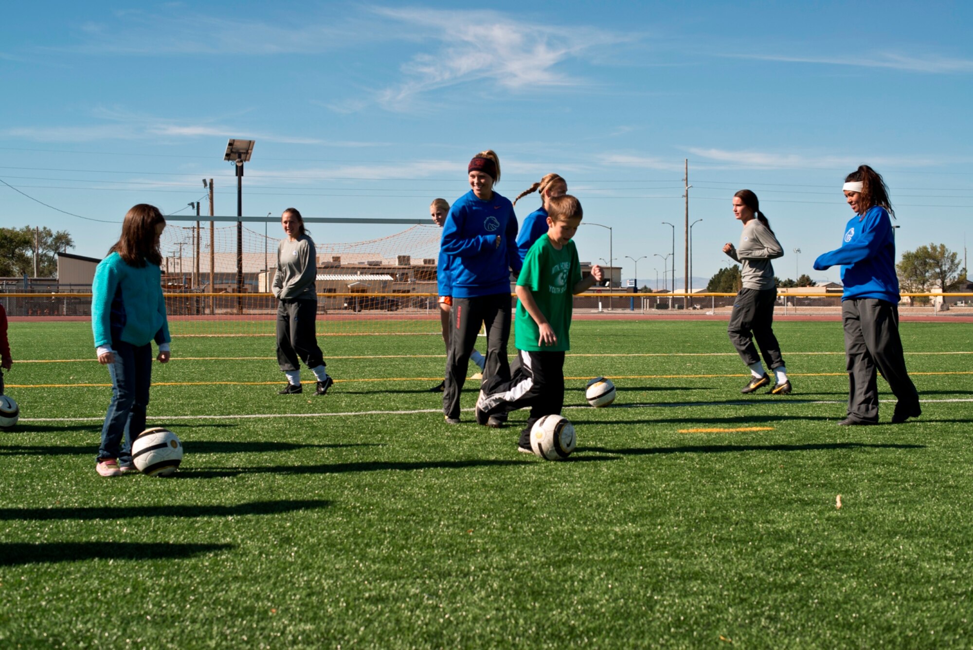 Cyrus Carlsness (green shirt) and Natalie Carlsness (blue sweatshirt) train with the Boise State University ladies soccer team at the Mountain Home Air Force Base, Idaho, fitness center, Oct. 5, 2013. The Broncos schooled the children in dribbling, passing, trapping, team-work and shooting skills. (U.S. Air Force photo by Master Sgt. Kevin Wallace/RELEASED)