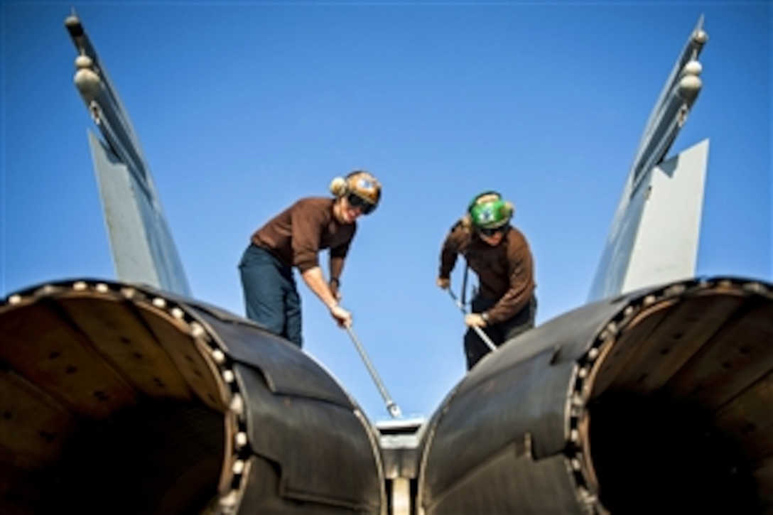 U.S. Navy Petty Officers 3rd Class Brandon Shreve, left, and U.S. Navy Petty Officer 3rd Class Brendon Holman clean an F/A-18C Hornet on flight deck of the aircraft carrier USS Harry S. Truman in the Gulf of Oman, Oct. 6, 2013. The Truman is deployed to the U.S. 5th Fleet area of responsibility, conducting maritime security operations, supporting theater security cooperation efforts.