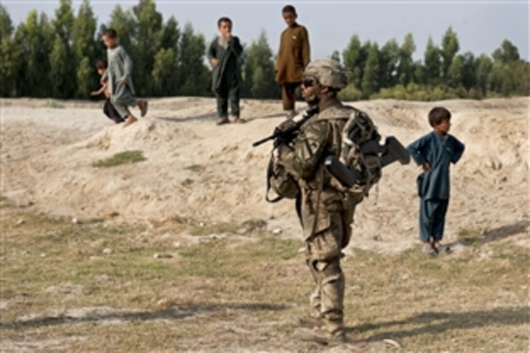 U.S. Army Pfc. Jazeron Knowles keeps watch while children play near him during an afternoon reconnaissance patrol in the vicinity of Forward Operating Base Fenty in Afghanistan's Nangarhar province, Sept. 29, 2013. Knowles is a rifleman assigned to the 1st Cavalry Division's 4th Squadron, 9th Cavalry Regiment, 2nd Armored Brigade Combat Team.