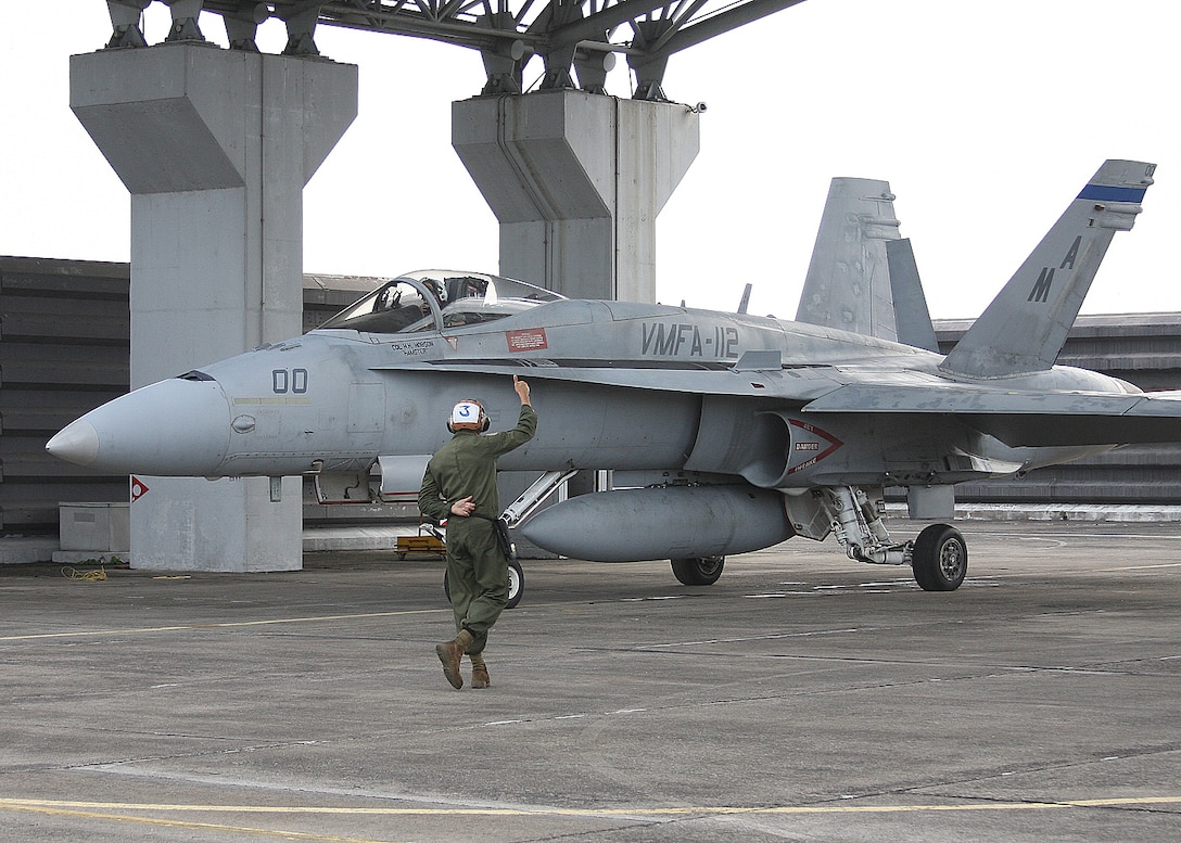 A Marine with Marine Fighter Attack Squadron 112 guides an aircraft along the flightline, Royal Malaysian Air Force Base Butterworth, Malaysia. The Cowboys returned to Iwakuni and are prepareing for their next deployment. 
