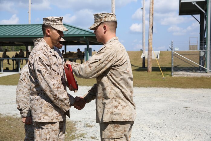 Capt. Thomas Q. Kearns (left), the director of the Battle Skills Training School, 2nd Marine Logistics Group, congratulates Cpl. Sean M. Stecher, a heavy equipment mechanic with 2nd Maintenance Battalion, Combat Logistics Regiment 25, 2nd MLG, on becoming his class’ honor graduate during a BSTS machine gunner course aboard Camp Lejeune, N.C., Oct. 4, 2013. Stecher graduated at the top of his class with a grade point average of 97.5 on written exams and a one minute and 30 second average disassembly and reassembly time.