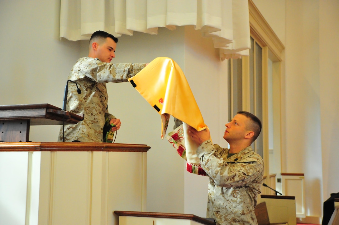Navy Petty Officer 1st Class Jason Cooper, religious program specialist, helps Navy Petty Officer 2nd Class Alexander Farmer prepare mass at the Marine Corps Memorial Chapel on Oct. 8, 2013. Cooper was selected as the Headquarters Marine Corps National Capital Region Senior Sailor of the Quarter.