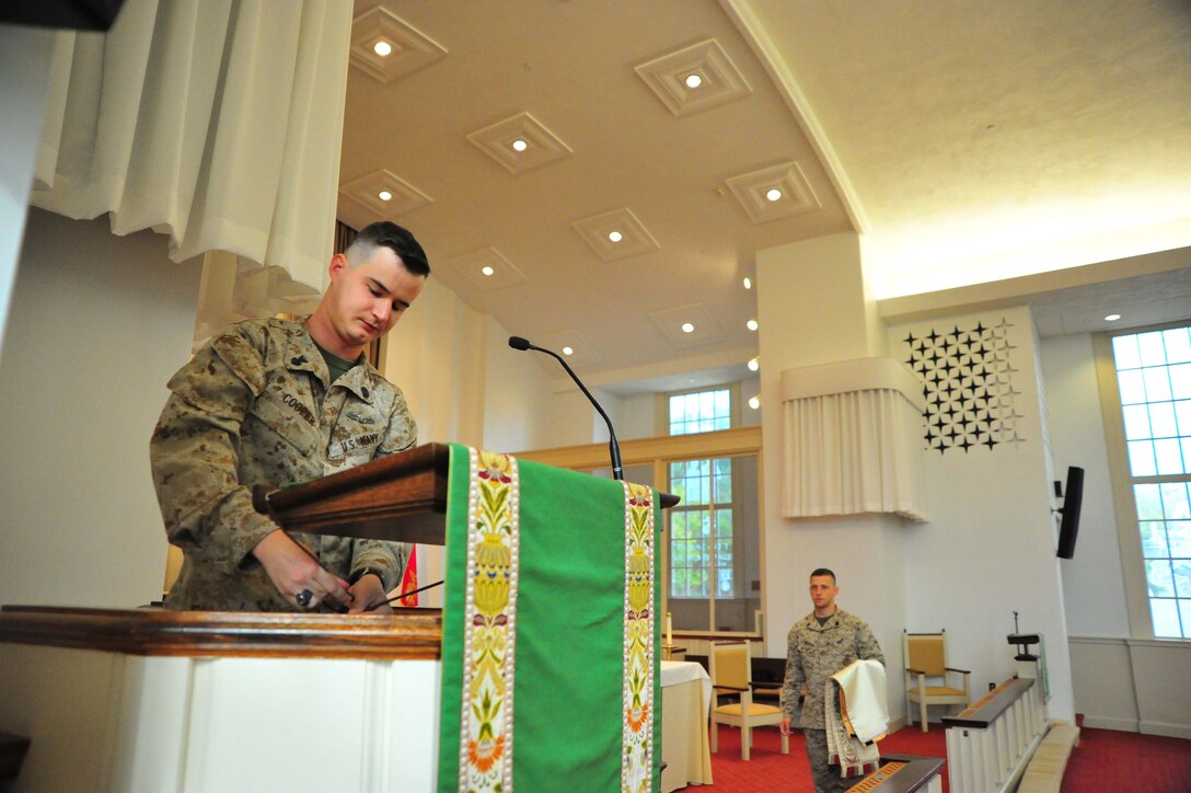Navy Petty Officer 1st Class Jason Cooper, religious program specialist, helps Navy Petty Officer 2nd Class Alexander Farmer prepare mass at the Marine Corps Memorial Chapel on Oct. 8, 2013. Cooper was selected as the Headquarters Marine Corps National Capital Region Senior Sailor of the Quarter.