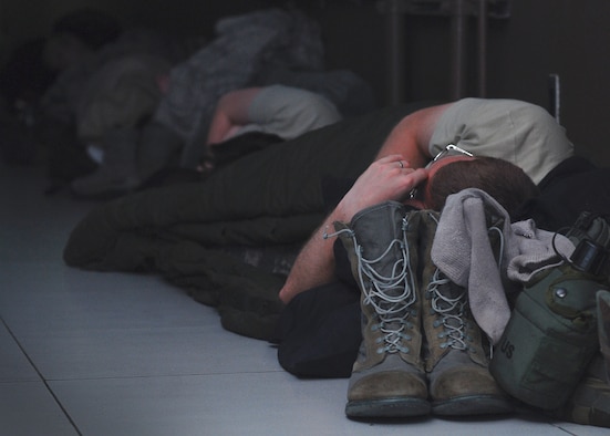 An Airman from the 694th Intelligence, Surveillance and Reconnaissance Group attempts to sleep in the hallway of the Korea Combat Operations Intelligence Center during a 24-hour lock-in training event held at Osan Air Base, Republic of Korea, Oct. 3, 2013. The lock-in required intelligence Airmen to test their ability to execute their mission while remaining within their operations center overnight. Airmen practiced wartime skills to include contamination control procedures, mission oriented protective posture gear driving, and individual preparations for sustained contingency operations. (U.S. Air Force photo/1st Lt. Kay M. Nissen)