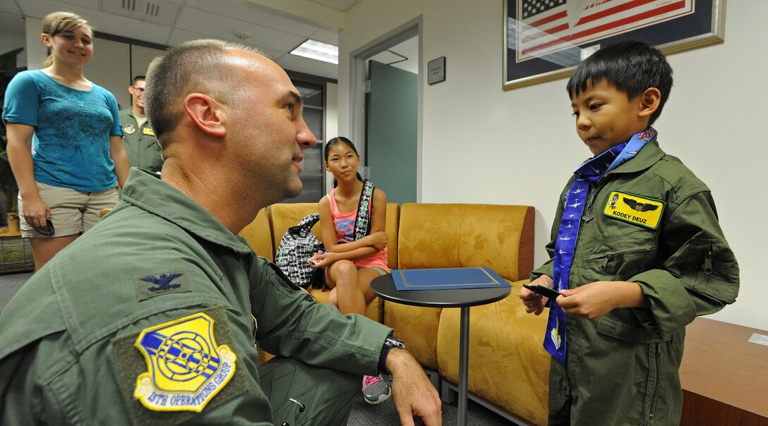 An “Honorary Squadron Membership” certificate, flight patch and aviator scarf was presented to Kodey Deuz a child battling aortic stenosis, aortic insufficiency and mitral regurgitation, by Col. Mike Merritt, 15th Operations Group commander, left, at the KC-135 Squadron building, Joint Base Pearl Harbor-Hickam, Hawaii, Oct. 4, 2013. Kodey and family were guests of the 15th Wing as part of the Pilot for a Day program that gives children with serious or chronic conditions a special day and a break from whatever challenges they may face. (U.S. Air Force photo/Tech. Sgt. Jerome S. Tayborn)