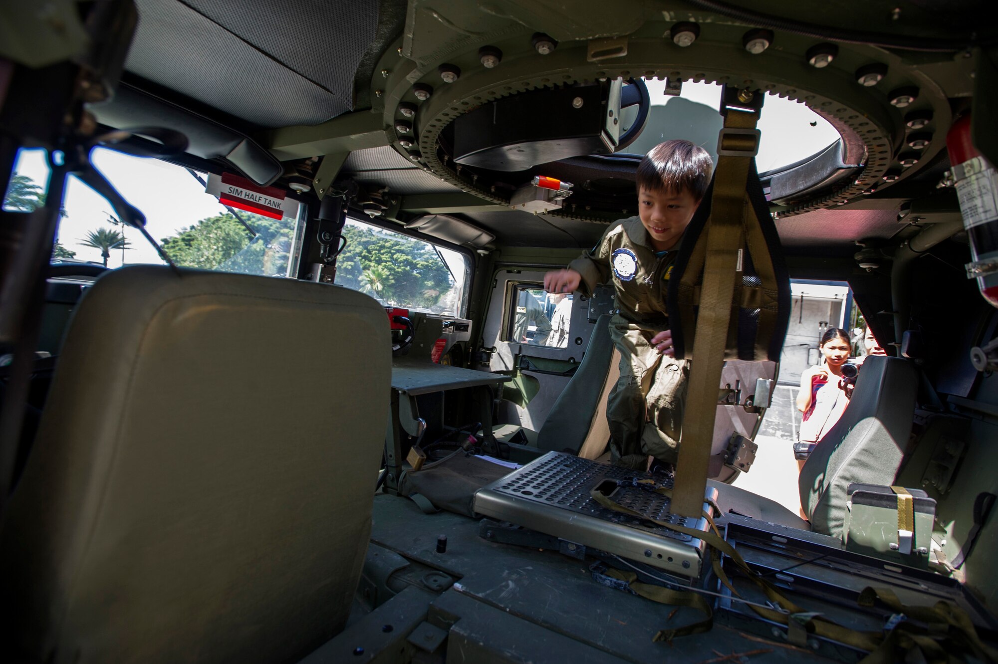 Kodey Deuz, a child battling aortic stenosis, aortic insufficiency and mitral regurgitation, center, hops into an up-armored HUMVEE during a tour of the Explosive Ordnance Disposal work center facility, as part of the Pilot for a Day program at Joint Base Pearl Harbor-Hickam, Hawaii, Oct. 4, 2013. The Pilot for a Day program focuses on children who have serious or chronic conditions, with the goal of giving each child a special day and a break from whatever challenges they may face. (U.S. Air Force photo/Tech. Sgt. Jerome S. Tayborn)