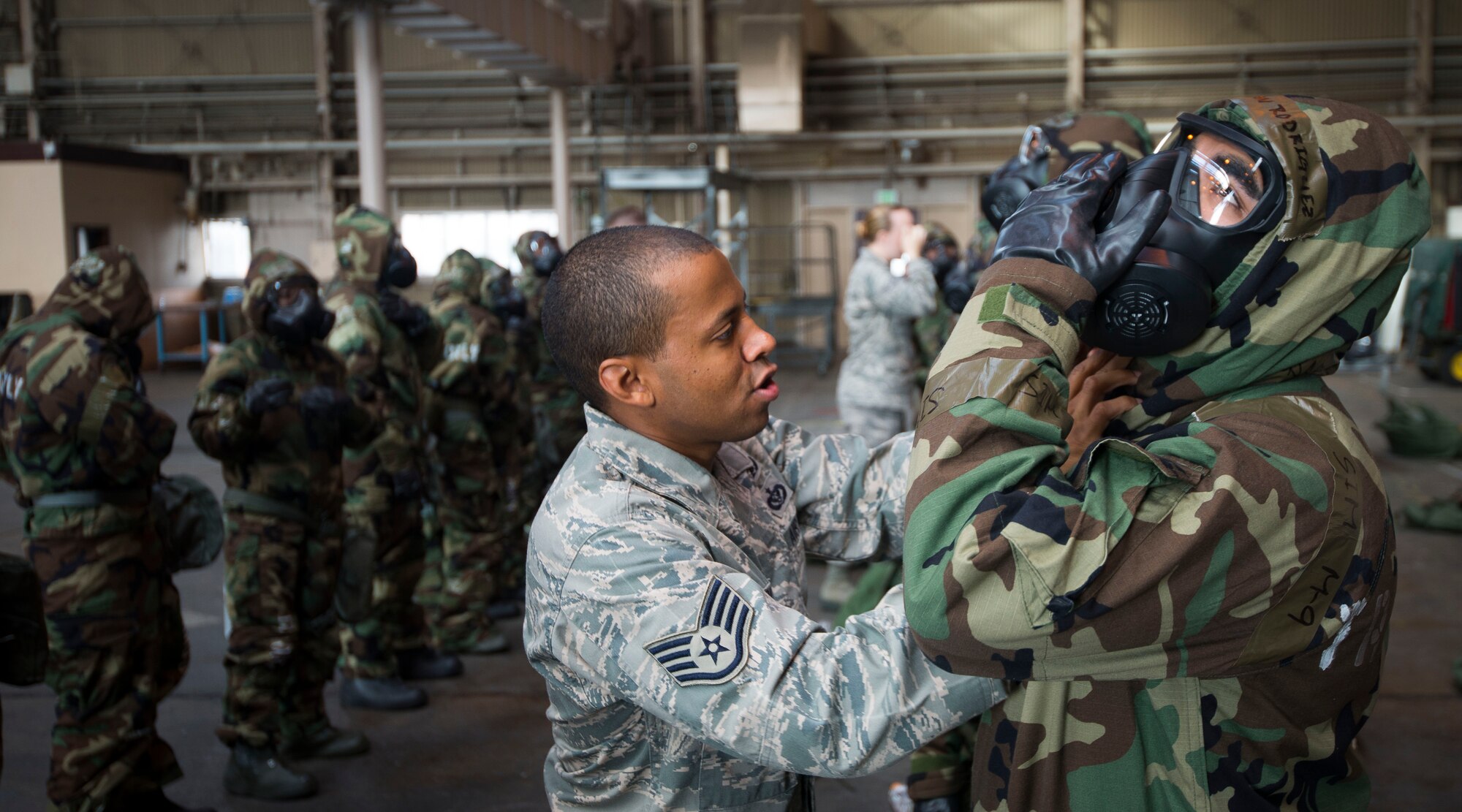 Staff Sgt. Sheraz Cedeno, 374th Civil Engineer Squadron ability to survive and operate (ATSO) instructor, inspects Airmen's chemical gear during ATSO training Oct. 9, 2013 at Yokota Air Base, Japan. Cedeno checked each members' mask to ensure a good seal was achieved. (U.S. Air Force photo by Staff Sgt. Chad C. Strohmeyer/Released)
