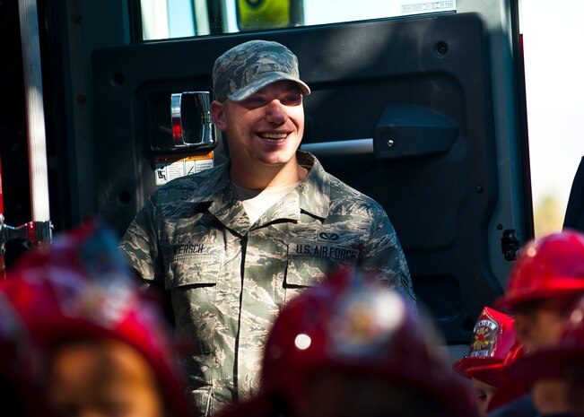 Airman 1st Class Eric Wiersch, 99th Civil Engineer Squadron firefighter, smiles as he explains to the children the capabilities of a fire truck at the child development center Oct. 8, 2013, at Nellis Air Force Base, Nev. The 2013 Fire Prevention Week theme is "prevent kitchen fires," 99 CES firefighters will teach the base populace how to keep cooking fires from starting in the first place.  (U.S. Air Force photo/Senior Airman Brett Clashman)
