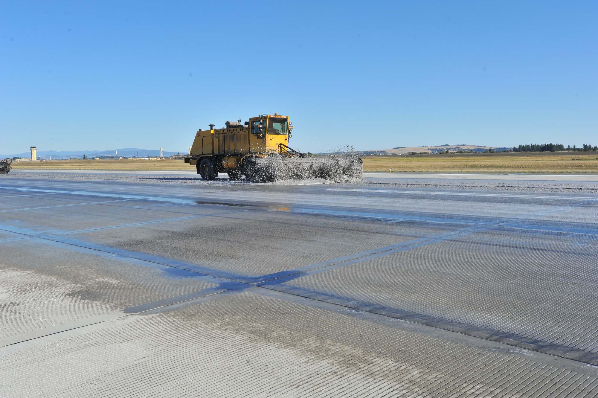 A snow broom scrubs the runway to enhance the chemical reaction during the flightline rubber removal process Oct. 4. The 92nd Civil Engineer Squadron snow barn team gathered with the 92nd CES fire department to conduct rubber removal on more than 4,000 feet of Fairchild’s flightline. (U.S. Air Force photo by Staff Sgt. Veronica Montes)