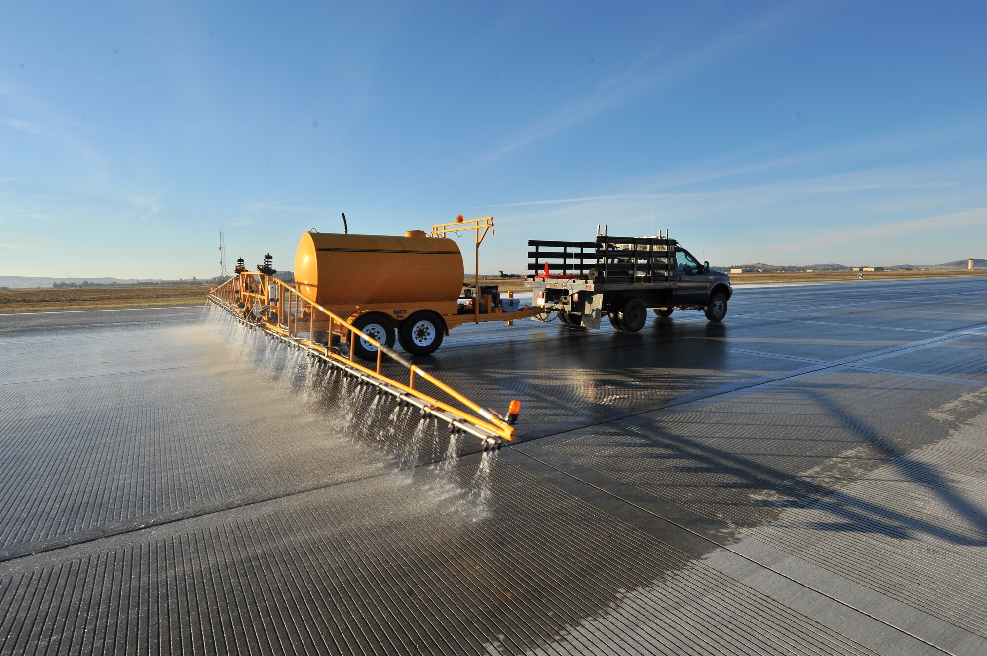 A De-icing truck sprays water on the runway to enhance the chemical reaction during the flightline rubber removal process, Oct. 4, at Fairchild Air Force Base, Wash. The 92nd Civil Engineer Squadron snow barn team gathered with the 92nd CES fire department to conduct rubber removal on more than 4,000 feet of Fairchild’s flightline. (U.S. Air Force photo by Staff Sgt. Veronica Montes)