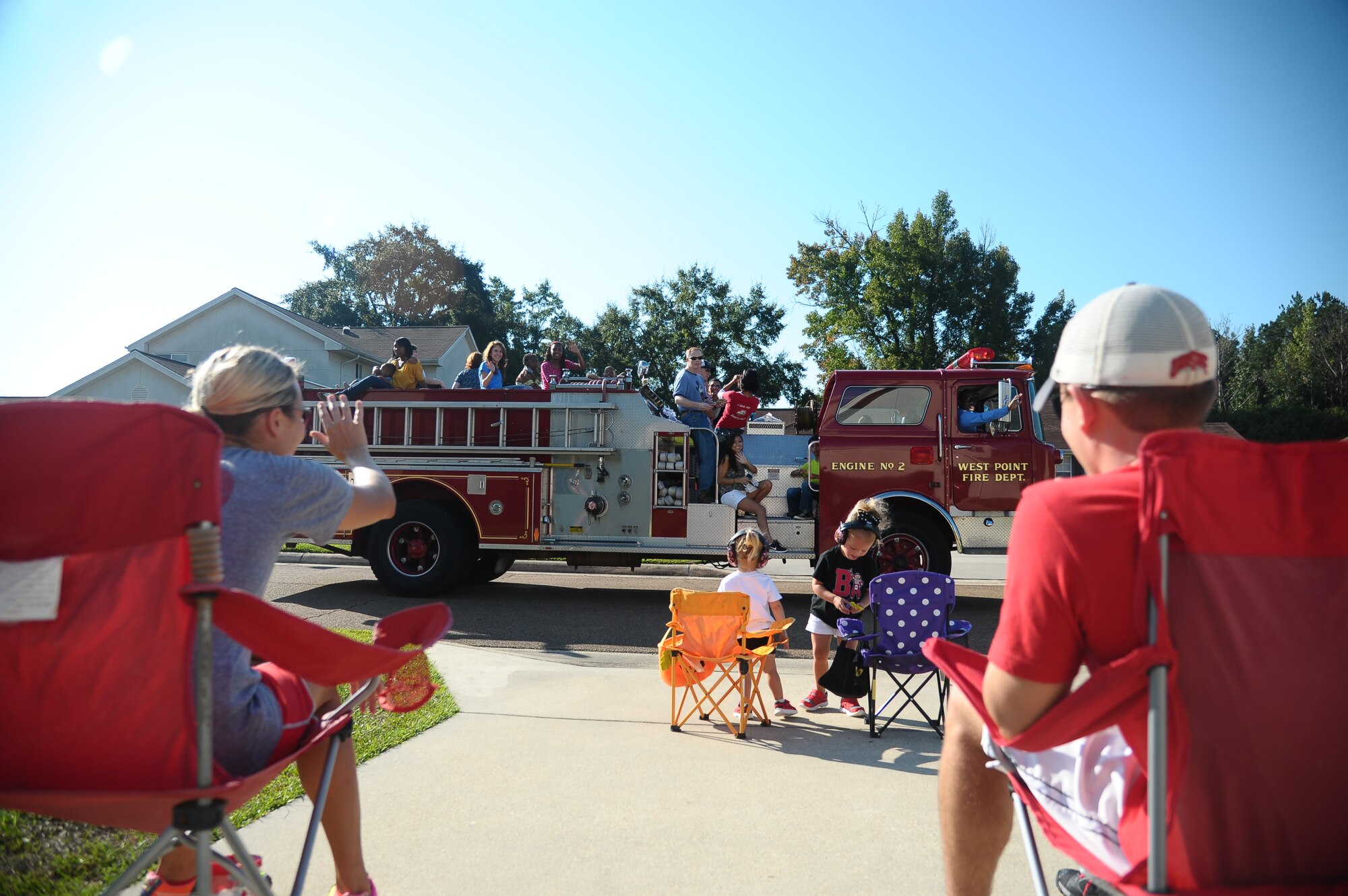 Residents of Columbus Air Force Base Housing wave as a parade of Fire trucks and vehicles pass by before the Fire Station Open House on Oct. 5. Festivities kicked off Saturday morning to celebrate the start of Fire Prevention Week. (U.S. Air Force Photo/Airman 1st Class Stephanie Englar)