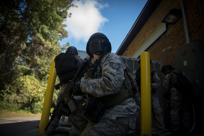 Staff Sgt. Perry Aston, 1st Combat Camera Squadron combat photographer, watches out for hostile forces attacking from the rear during an exercise Oct. 4, 2013, at Joint Base Charleston, S.C. Airmen from the 1st CTCS trained on how to document outside the wire operations by patrolling through four villages and engaging hostile forces in simulated training. The exercise was geared to familiarize and test the Airmen on their ability to operate outside the wire as combat documentation specialists. (U.S. Air Force photo/Tech. Sgt. Rasheen Douglas)
