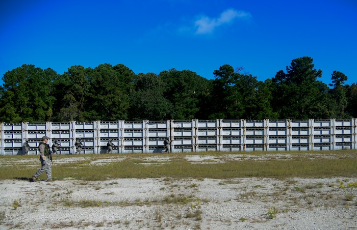 Airmen from the 1st Combat Camera Squadron simulate practicing clearing procedures while on a patrol on Oct. 4, 2013, at Joint Base Charleston - Weapons Station, S.C. Combat Camera Airmen trained on how to document outside the wire operations by patrolling through four villages and simulated hostile forces in simulated training. The exercise was geared to familiarize and test the Airmen on their ability to operate outside the wire as combat documentation specialists. (U.S. Air Force photo/Tech. Sgt. Rasheen Douglas)