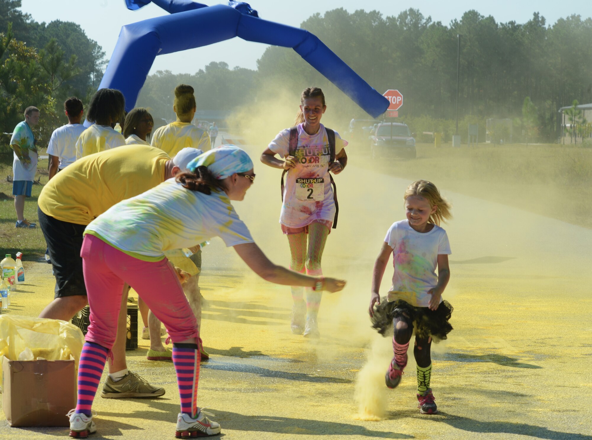Participants of the Shut Up and Color Run 5K pass the last color station while getting doused in yellow powder, Shaw Air Force Base, S.C., Oct. 5, 2013. About 500 people came out for the Shut Up and Color Run, where participants were doused with six different colors by the end of the 5K run. (U.S. Air Force photo by Senior Airman Tabatha Zarrella/Released)
