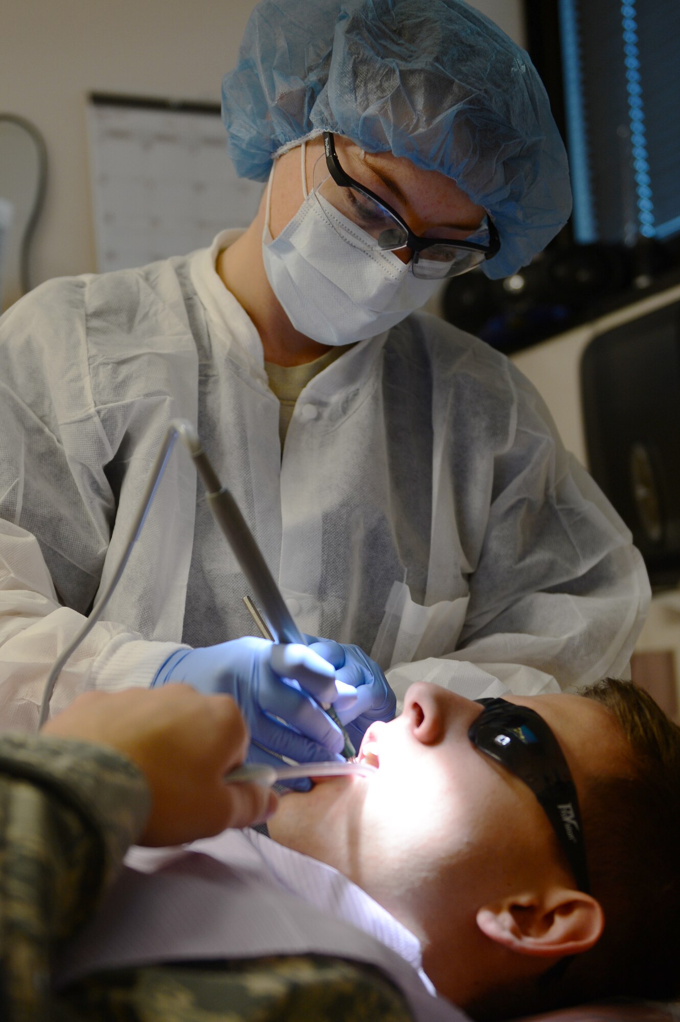 Staff Sgt. Tonya Collett, 20th Dental Squadron dental technician, uses an ultrasonic tool, called a cavitron, to clean the teeth of Senior Airman Colin Casey, 20th DS lab technician, at Shaw Air Force Base, S.C., Sept. 30, 2013. A cavitron uses water vibrations to break apart plaque. (U. S. Air Force photo by Airman 1st Class Krystal M. Jeffers/Released)