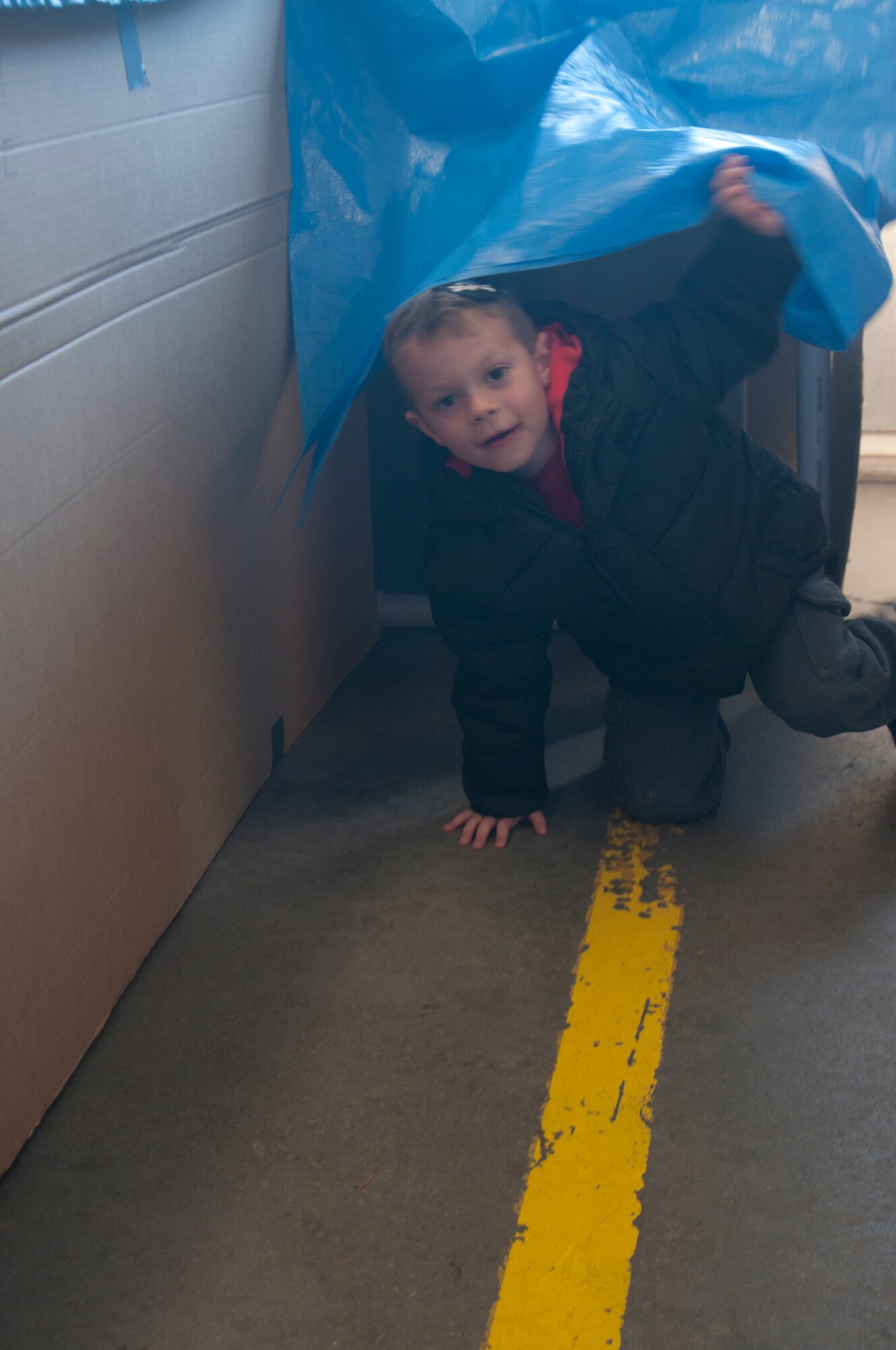 Kyler Blanda, son of Tech. Sgt. Jeff Blanda, 90th Maintenance Operations Squadron instructor, exits a tarp-covered maze in F.E. Warren Fire Station 2 after crawling his way through it during a fire department open house Oct. 5, 2013. The maze is filled with simulated smoke from a fog machine, and the maze is intended to simulate crawling through a smoke-filled room during a fire. The open house’s aim was to educate guests in fire safety and fire prevention. (U.S. Air Force photo by Airman 1st Class Jason Wiese)