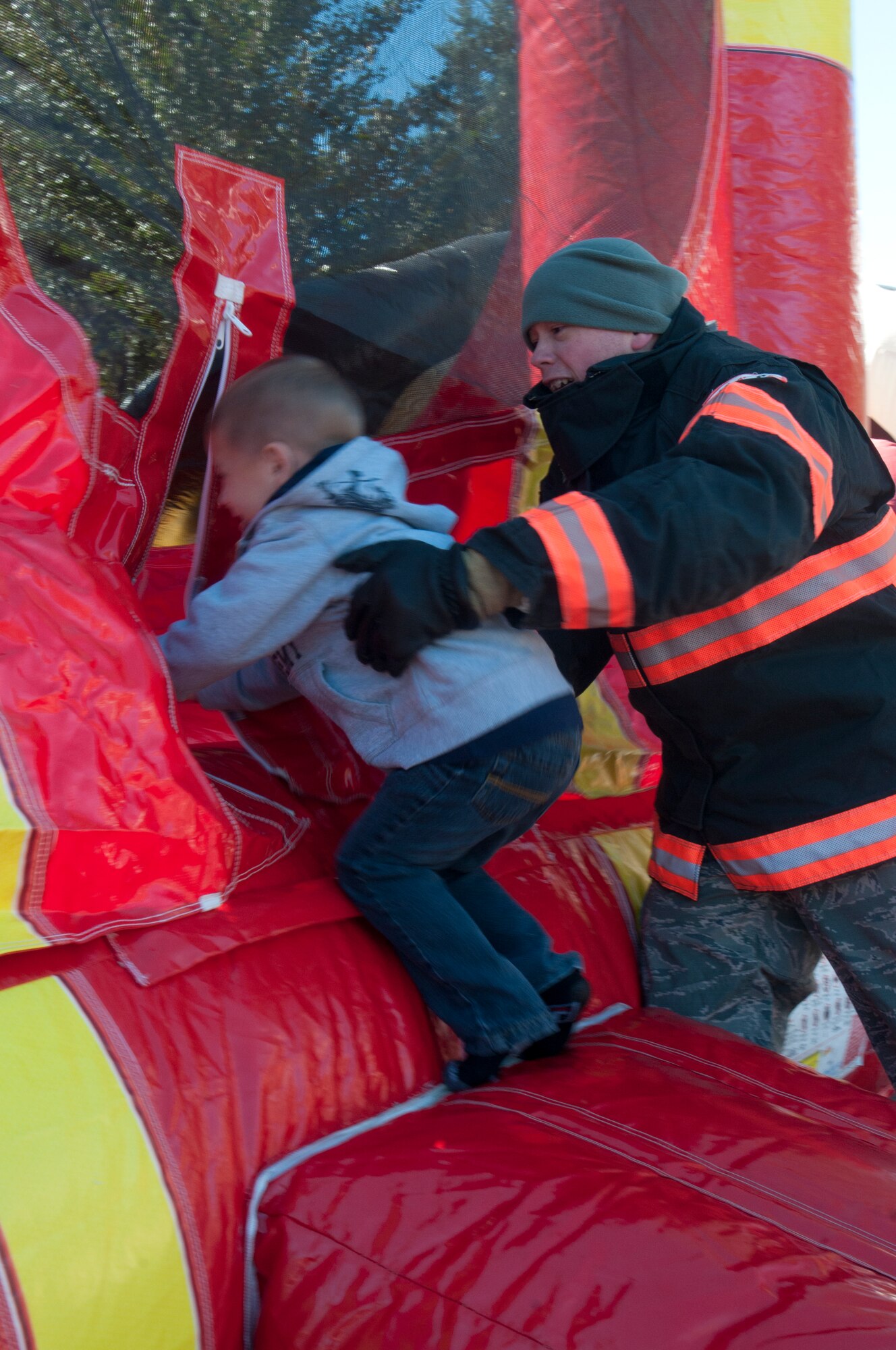 Senior Airman Troy Juhl, 90th Civil Engineer Squadron firefighter, helps Tyler Blair-Henley, son of Senior Airman Tim Henley, 90th Civil Engineer Squadron power production, into a fire hydrant-themed bounce house outside F.E. Warren Fire Station 2 Oct. 5, 2013.(U.S. Air Force photo by Airman 1st Class Jason Wiese)