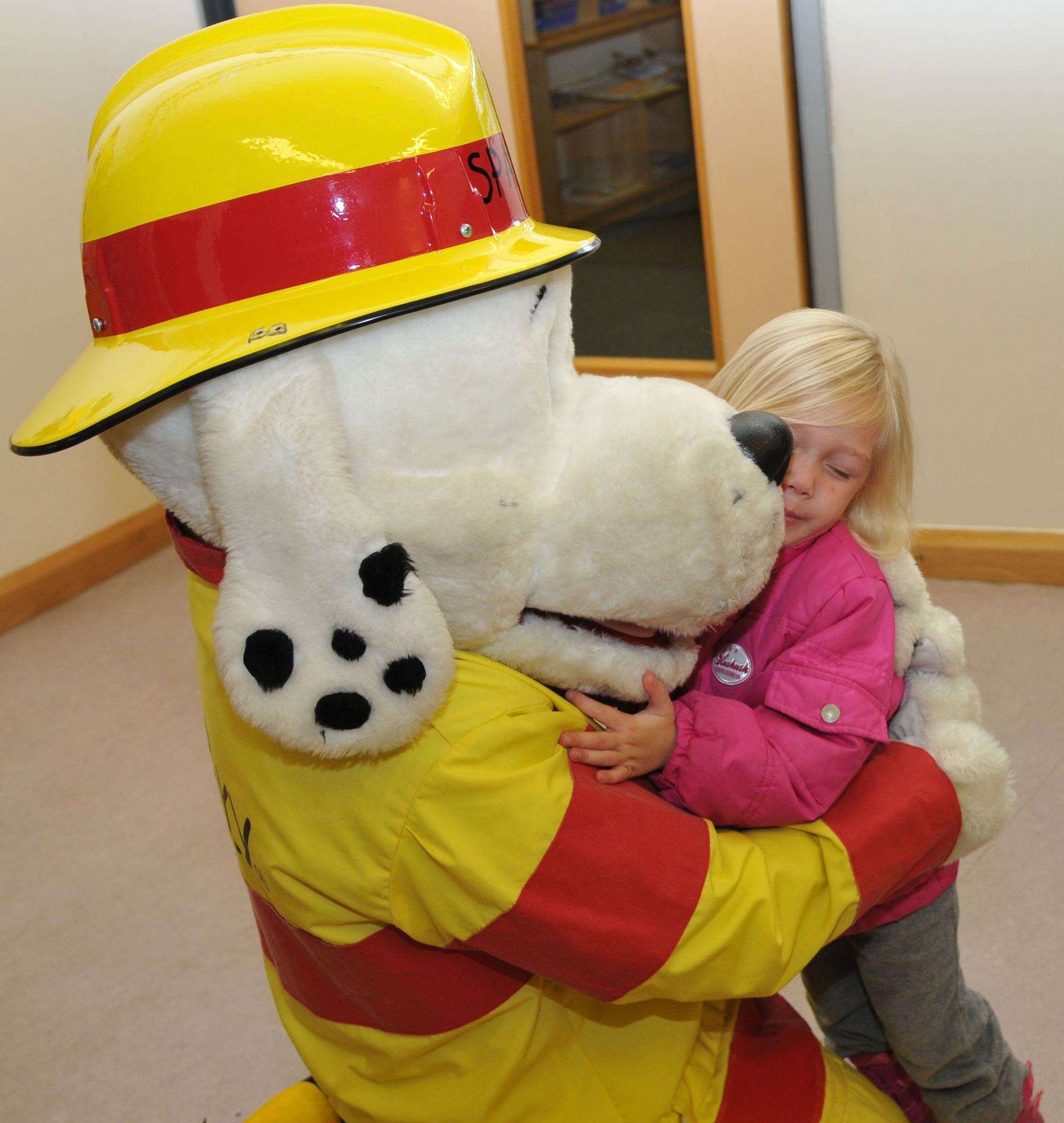 Caeleigh Davis, 3, daughter of Staff Sgt. Brian Davis, 95th Reconnaissance Squadron hydraulics journeyman from Okinawa, Japan, greets Sparky the Fire Dog, 100th Civil Engineer Squadron Fire Department mascot, with a hug Oct. 7, 2013, at the Child Development Center on RAF Mildenhall, England. Sparky visited the CDC as part of Fire Prevention Week. This year, the theme is learning to prevent kitchen fires.  (U.S. Air Force photo by Airman 1st Class Kelsey Waters/Released)