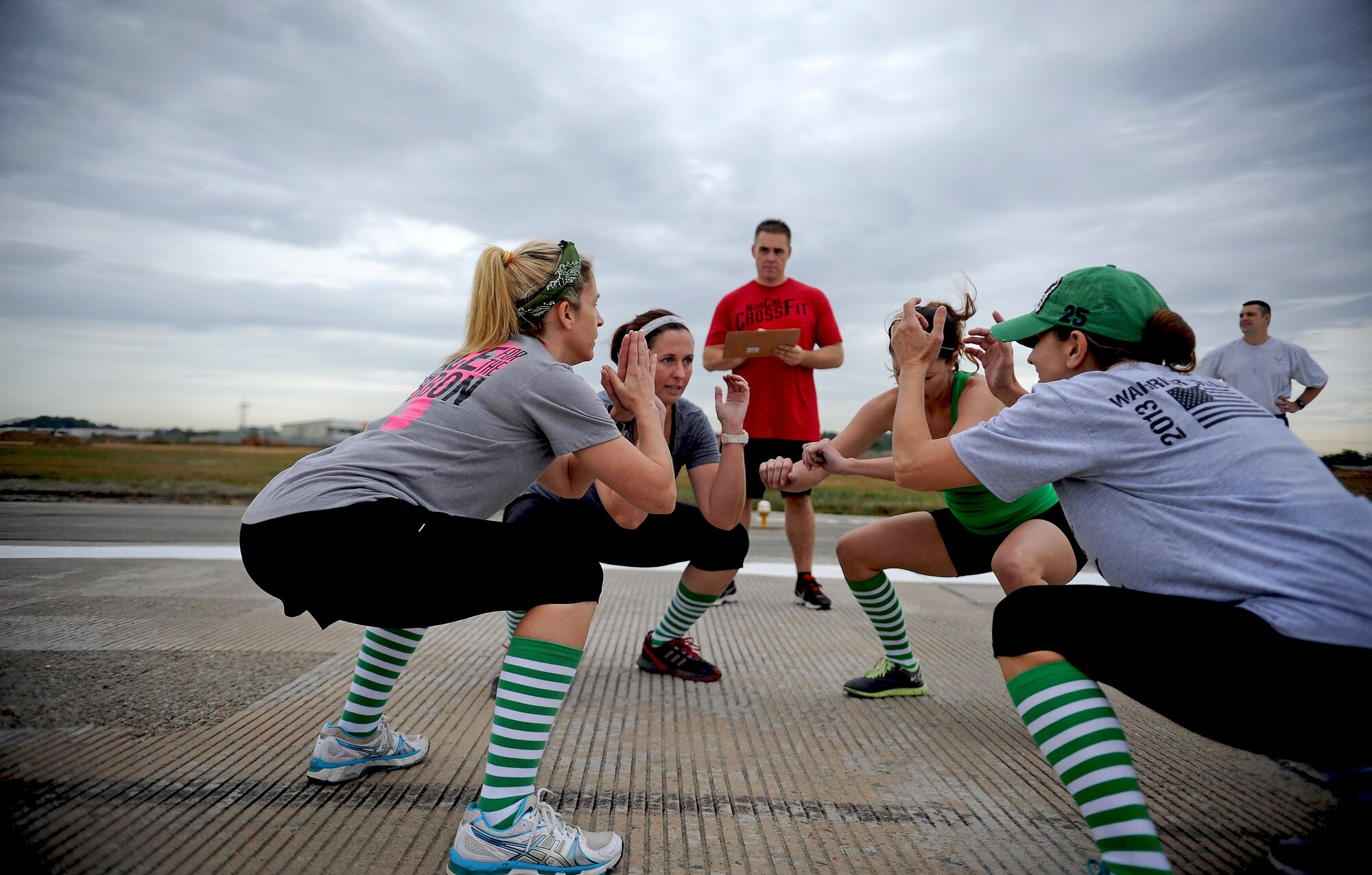 A team squats together as part of the Runway Fitness Challenge on the flight line at Osan Air Base, Republic of Korea, Oct. 7, 2013. The burpee broad jumps were the last exercise of the Runway Fitness Challenge, which was part of the Osan Warrior Challenge. (U.S. Air Force photo/Staff Sgt. Sara Csurilla)