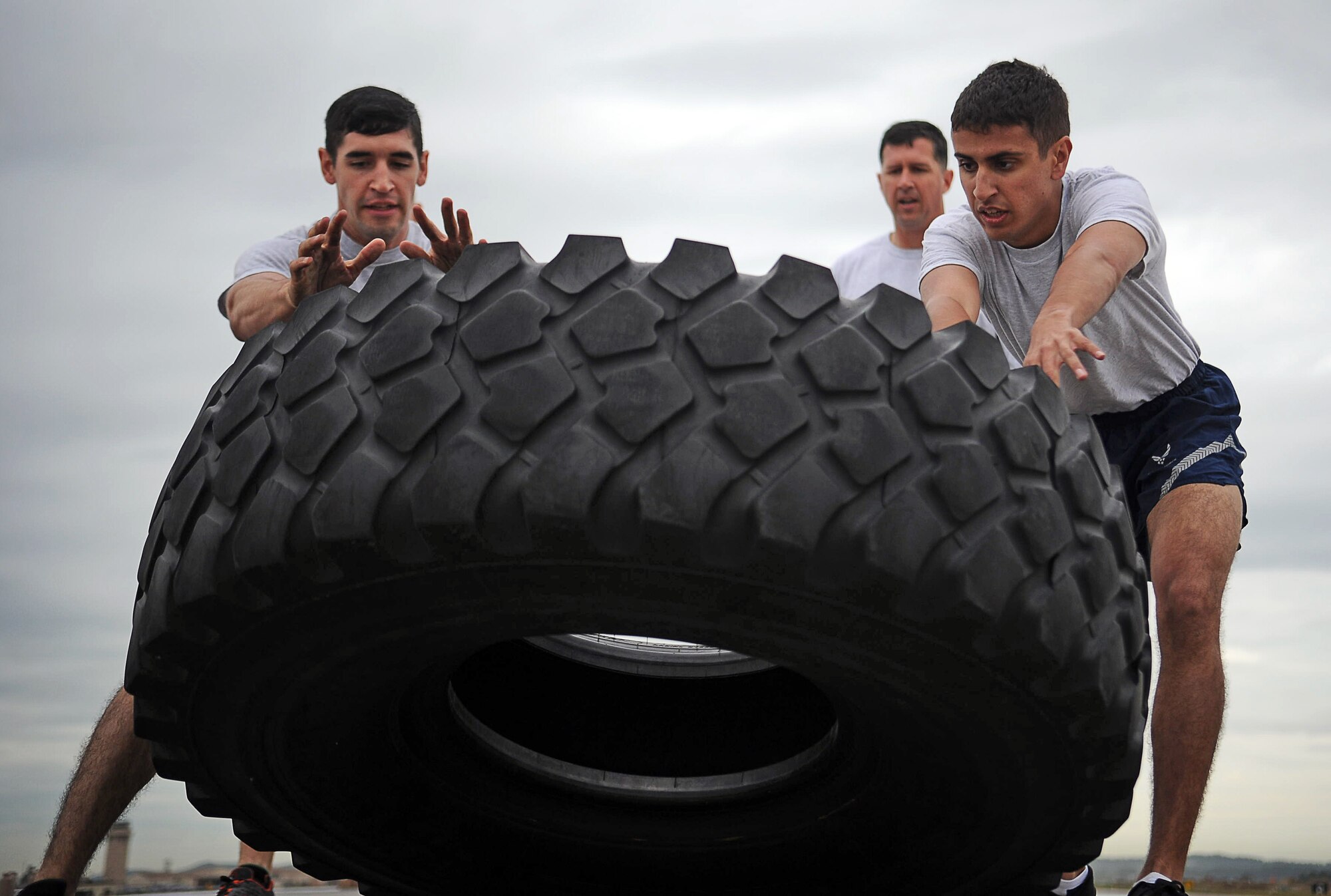 Osan Airmen flip a tire during the Runway Fitness Challenge on the flight line at Osan Air Base, Republic of Korea, Oct. 7, 2013. During the Runway Fitness Challenge, which was part of the Osan Warrior Challenge, teams of four raced against the clock to complete six different exercise stations under 25 minutes. (U.S. Air Force photo/Staff Sgt. Sara Csurilla)