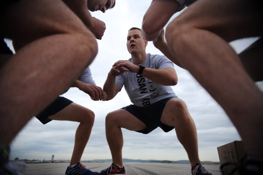 A team squats together as part of the Runway Fitness Challenge on the flight line at Osan Air Base, Republic of Korea, Oct. 7, 2013. The burpee broad jumps were the last exercise of the Runway Fitness Challenge, which was part of the Osan Warrior Challenge. (U.S. Air Force photo/Staff Sgt. Sara Csurilla)