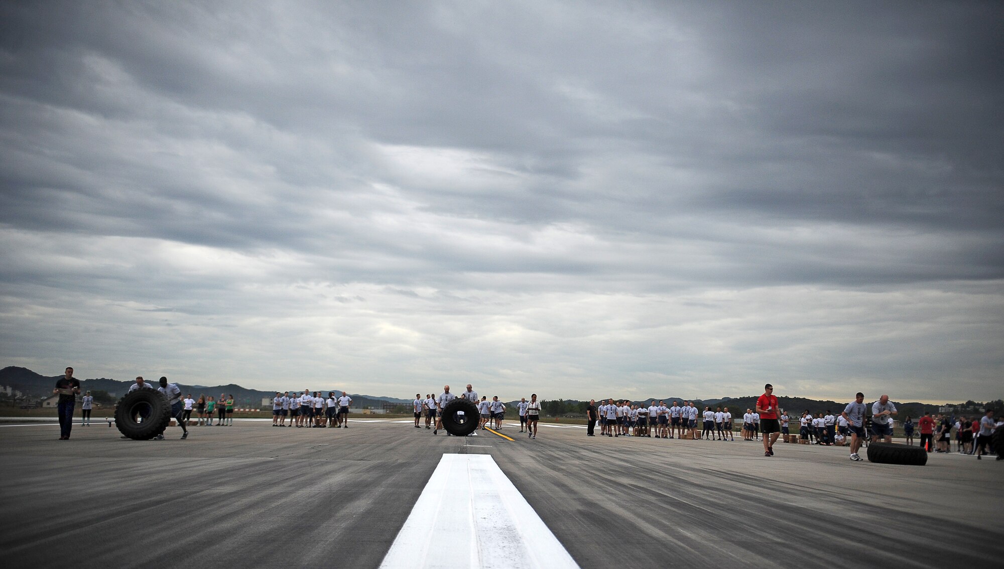 Four-man teams flip tires down the Osan flight line as part of the Runway Fitness Challenge at Osan Air Base, Republic of Korea, Oct. 7, 2013. The burpee broad jumps were the last exercise of the Runway Fitness Challenge, which was part of the Osan Warrior Challenge. (U.S. Air Force photo/Staff Sgt. Sara Csurilla)