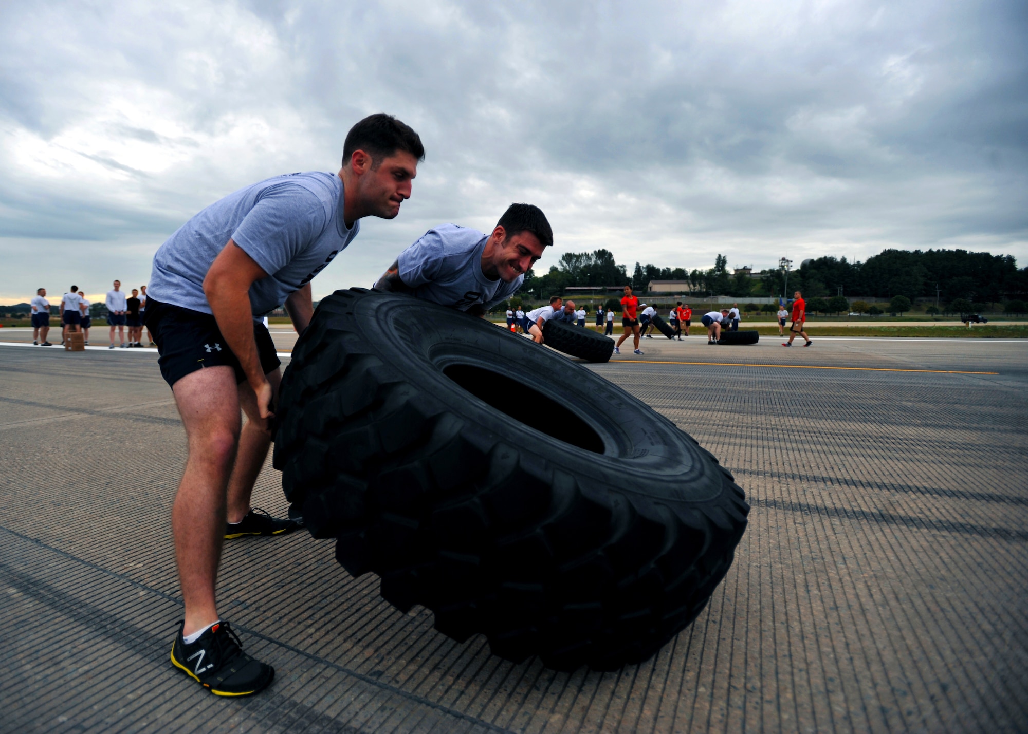 Staff Sgt. Travis Hirshlor, 694th Intelligence Support Squadron critical communications technician, and Tech. Sgt. Joseph Mcanally, 694th ISS assistant section chief of network operations, flip a tire during the Runway Fitness Challenge on the flight line at Osan Air Base, Republic of Korea, Oct. 7, 2013. During the Runway Fitness Challenge, which was part of the Osan Warrior Challenge, teams of four raced against the clock to complete six different exercise stations under 25 minutes. (U.S. Air Force photo/Senior Airman Siuta B. Ika)