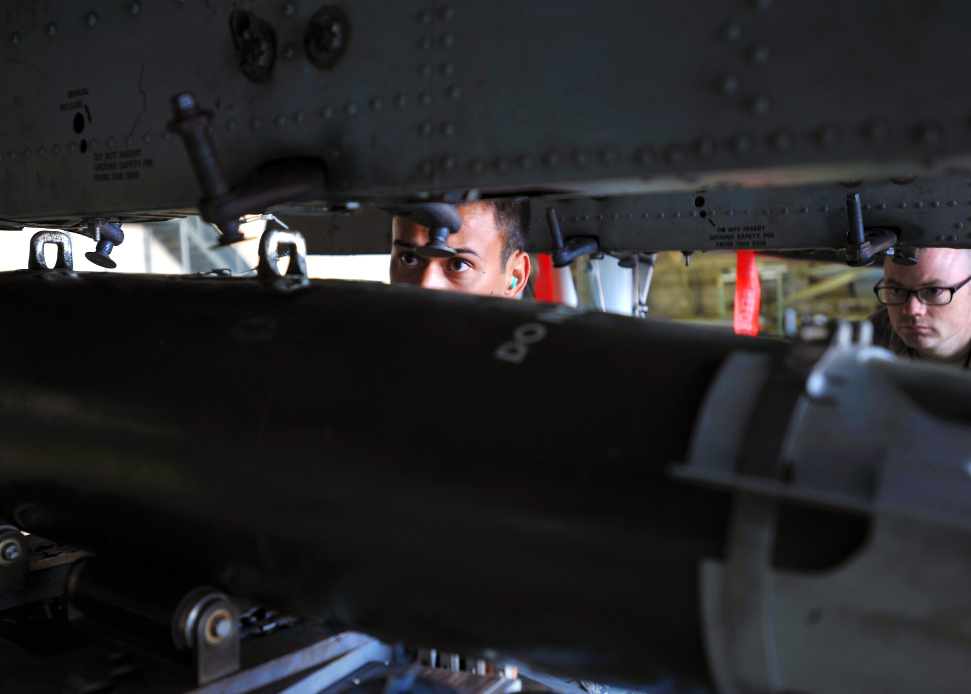 Senior Airman Wyatt McMillin, 25th Aircraft Maintenance Unit weapons load crew member, guides a munition onto an A-10 Thunderbolt during a quarterly weapons load crew competition at Osan Air Base, Republic of Korea, Oct. 4, 2013. During a weapons load crew competition, each member has a set of tasks to carry out and must work on a team of three or four, depending on the aircraft they are assigned to. (U.S. Air Force photo/Senior Airman Siuta B. Ika)