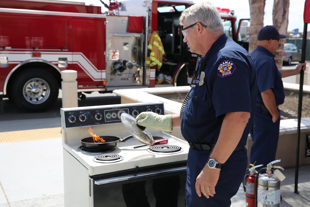 Lawrence Beal, a fire inspector with the Miramar Fire Department, demonstrates how to properly put out a stove fire outside the Marine Corps Exchange aboard Marine Corps Air Station Miramar, Oct. 8. The fire department is focusing on kitchen fires for this year’s Fire Prevention Week Oct. 7-11. 