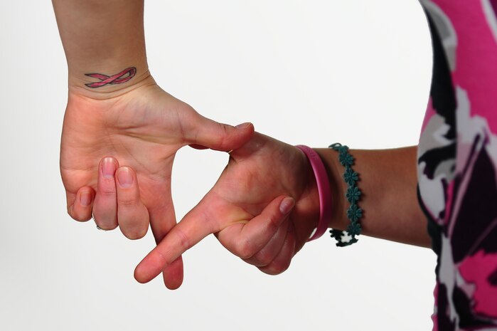 Jessica Newbury, forms her fingers in the shape of the Breast Cancer Awareness symbol Oct. 9, 2013, at Joint Base Charleston – Air Base, S.C. Newbury joined the United States Navy in 2003 and served for eight years as a machinist mate before her medical retirement. Newbury is a breast cancer survivor and continues to be an inspiration for those that know her and her story.  (U.S. Air Force photo/ Airman 1st Class Chacarra Neal)