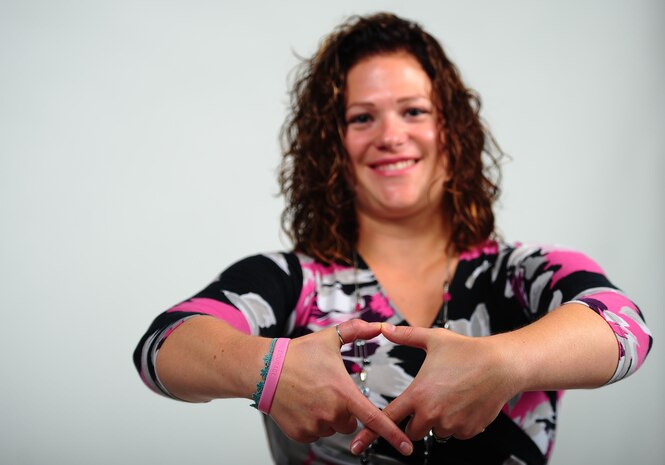 Jessica Newbury, forms her fingers in the shape of the Breast Cancer Awareness symbol Oct. 9, 2013, at Joint Base Charleston – Air Base, S.C. Newbury joined the United States Navy in 2003 and served for eight years as a machinist mate before her medical retirement. Newbury is a breast cancer survivor and continues to be an inspiration for those that know her and her story.  (U.S. Air Force photo/ Airman 1st Class Chacarra Neal)