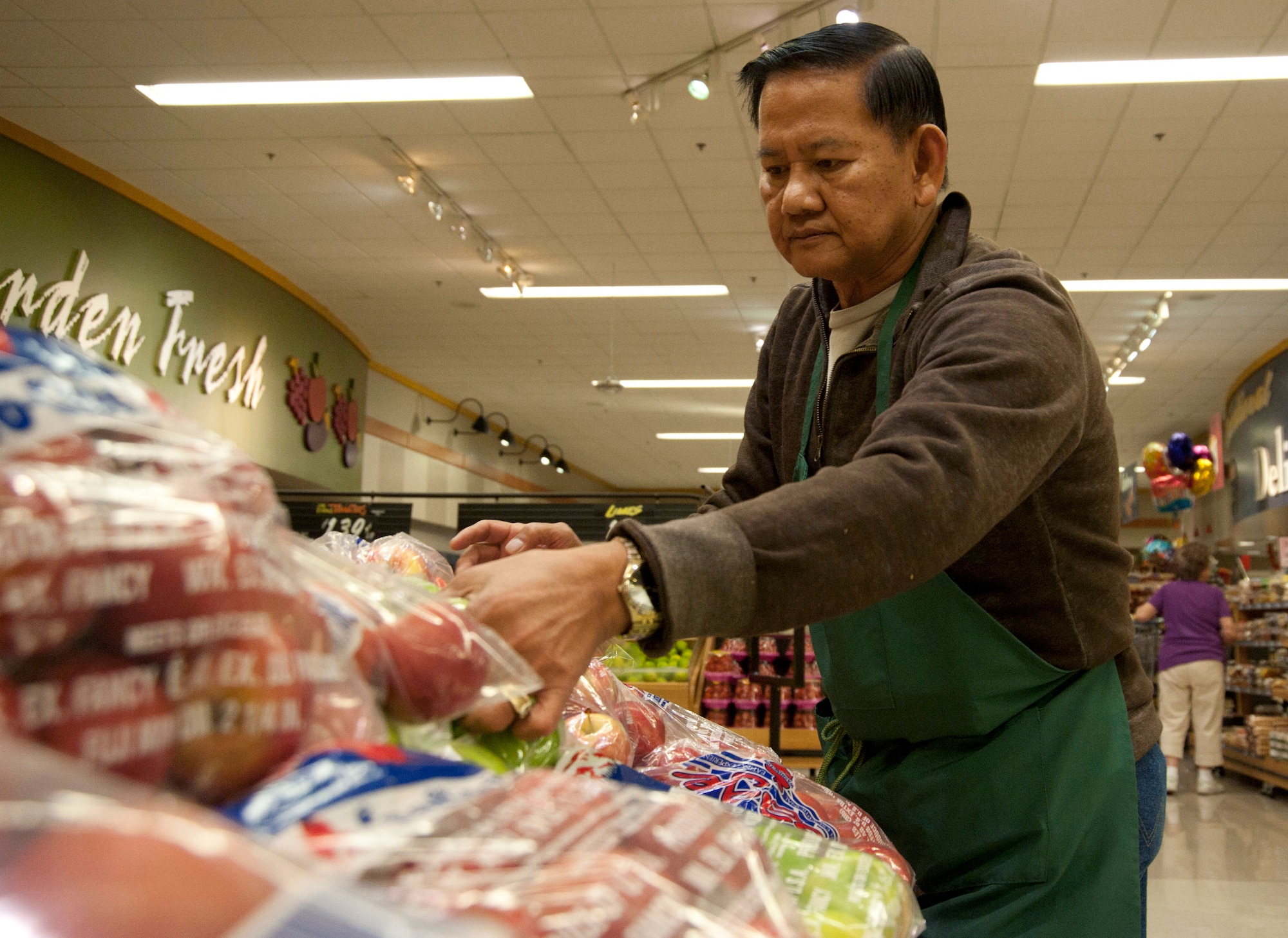 Edgar Yanga, commissary store worker, arranges bags of apples in the commissary produce section Oct. 9, 2013, at Nellis Air Force Base, Nev. The commissary reopened Oct. 7 after being closed for five days due to the government shutdown. (U.S. Air Force photo by Airman 1st Class Timothy Young)