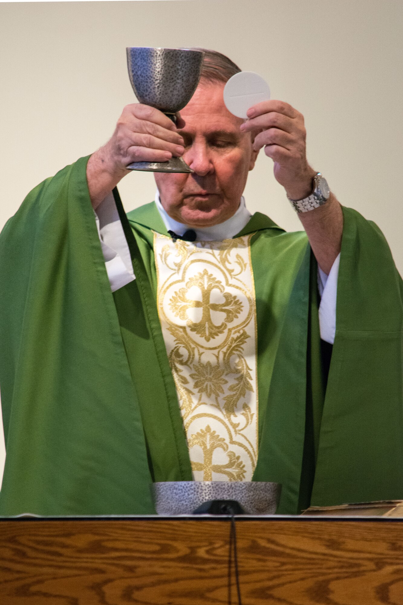 Father Donald Moss holds up bread and wine during a Catholic mass Sept. 22, 2013 at Scott Air Force Base, Ill. Moss and chaplains with the 375th Air Mobility Wing chapel provide religious, spiritual and mental support for Scott AFB members and their families, which includes religious services and counseling. (U.S. Air Force photo/Staff Sgt. Jonathan Fowler)