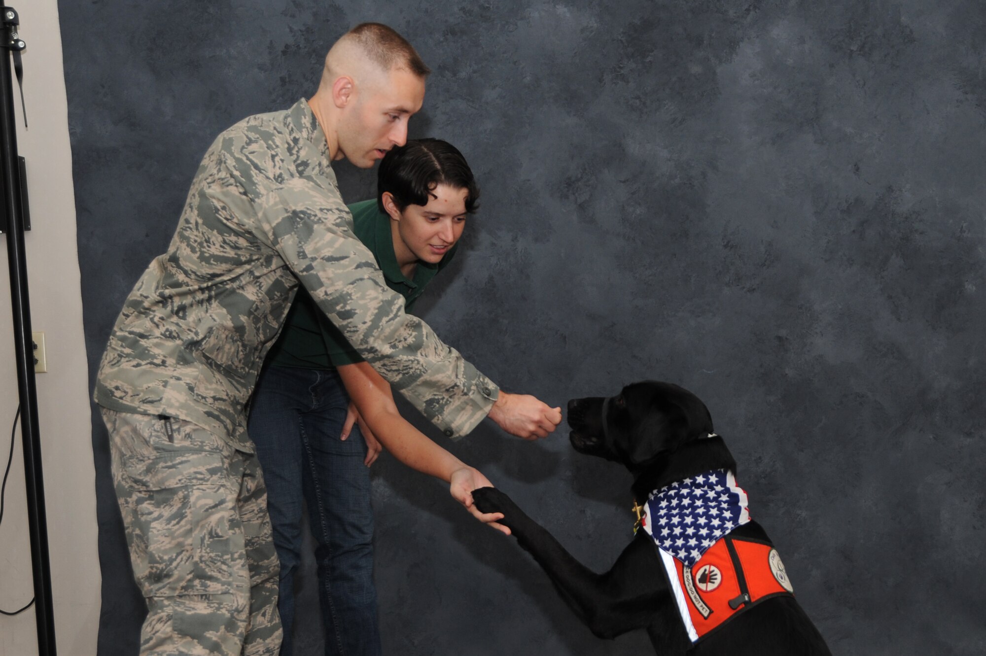 Emily Cost rewards their foster dog, Bexley after following the command of shaking his paw with 1st Lt. Robert Cost at Scott Air Force Base, Sep. 30, 2013. The training the dogs go through averages to about $15- 25,000 per dog, but is free to the partner who adopts the dog. (U.S. Air Force photo/Airman Megan Friedl)