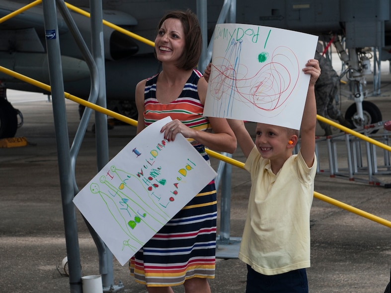 Meagan and Matthew Sackenheim, wife and son of U.S. Air Force Capt. Michael Sackenheim , 74th Fighter Squadron A-10C Thunderbird II pilot, hold welcome-home signs at Moody Air Force Base, Ga., Oct. 8, 2013. Meagan and Matthew were among many friends and family who gathered to welcome their Airmen after six months of deployment. (U.S. Air Force photo by Airman First Class Alexis Grotz/Released)