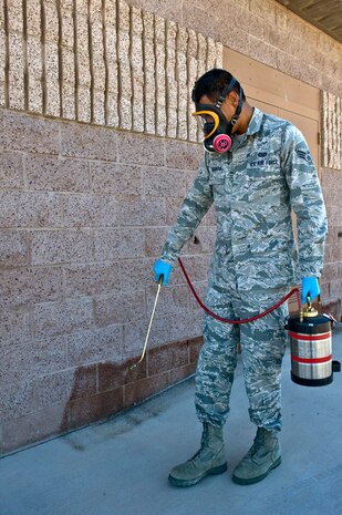 Senior Airman Jason Urquiola, 99th Civil Engineer Squadron pest management journeyman, sprays insecticide along the wall of the pest management building Oct. 2, 2013, at Nellis Air Force Base, Nev. Pest management spray insecticide inside and outside of buildings on base as needed. (U.S. Air Force photo by Senior Airman Matthew Lancaster)